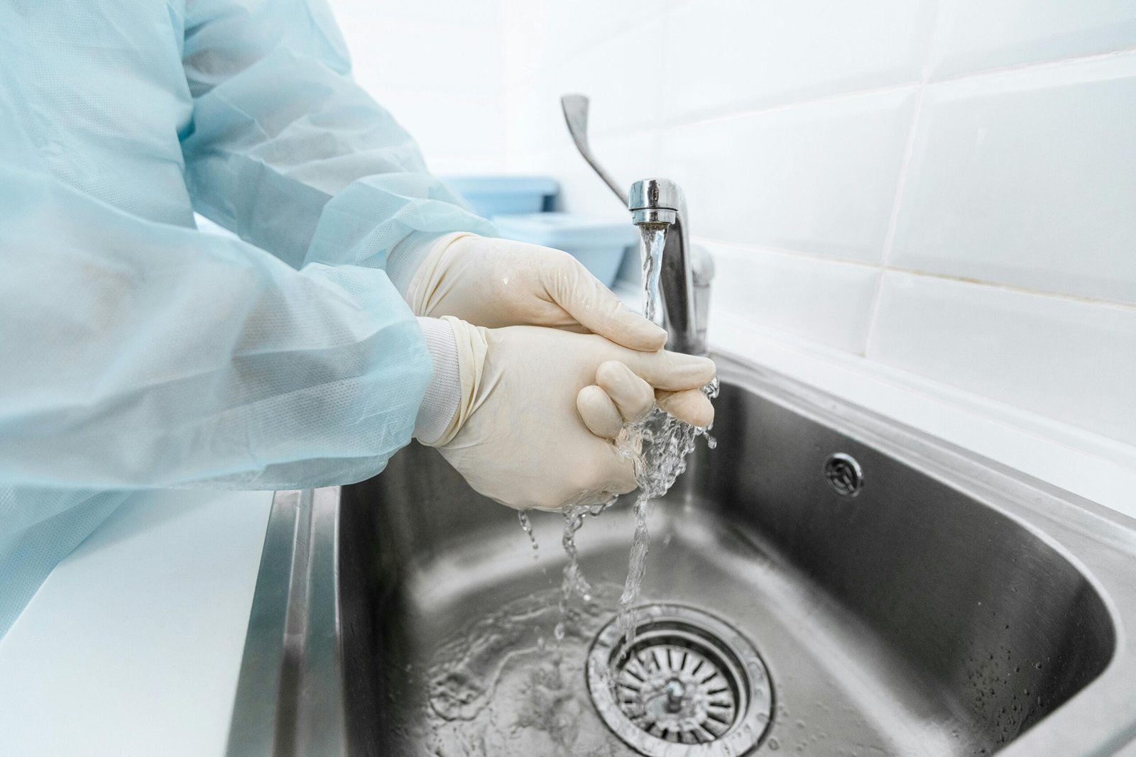 Medical professional washing hands under running water to ensure hygiene.